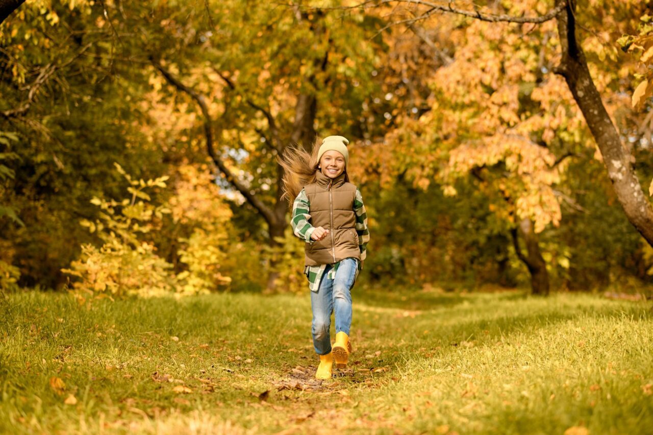 A girl in warm clothes playing in the park