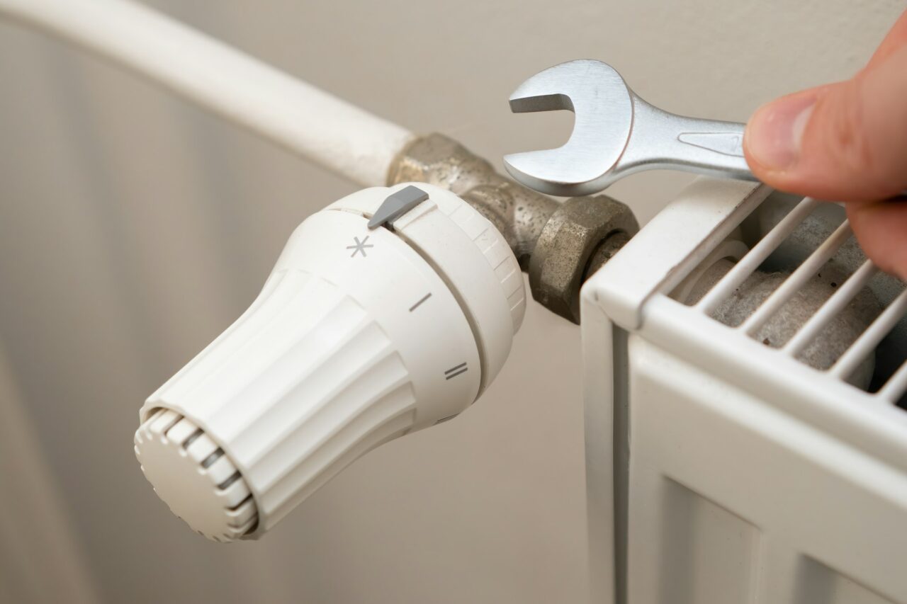 Closeup of heating radiator valve for comfortable temperature regulation and wrench to repair