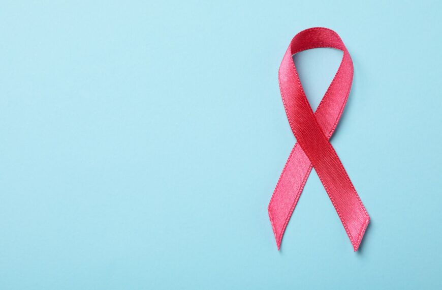 Pink awareness ribbon on blue background, space for text
