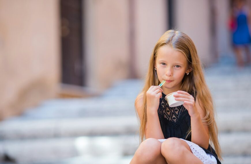 Adorable girl eating ice-cream outdoors at summer in the city