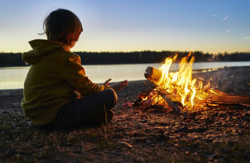 Argentina, Patagonia, Concordia, boy sitting at camp fire at a lake
