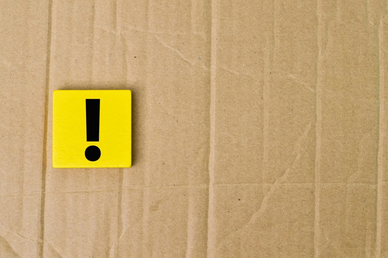 Exclamation mark drawn on wooden board over cork background with copy space.