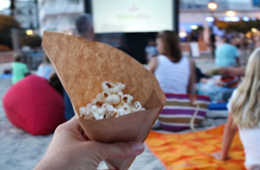 Hand holding popcorn at an outdoors cinema