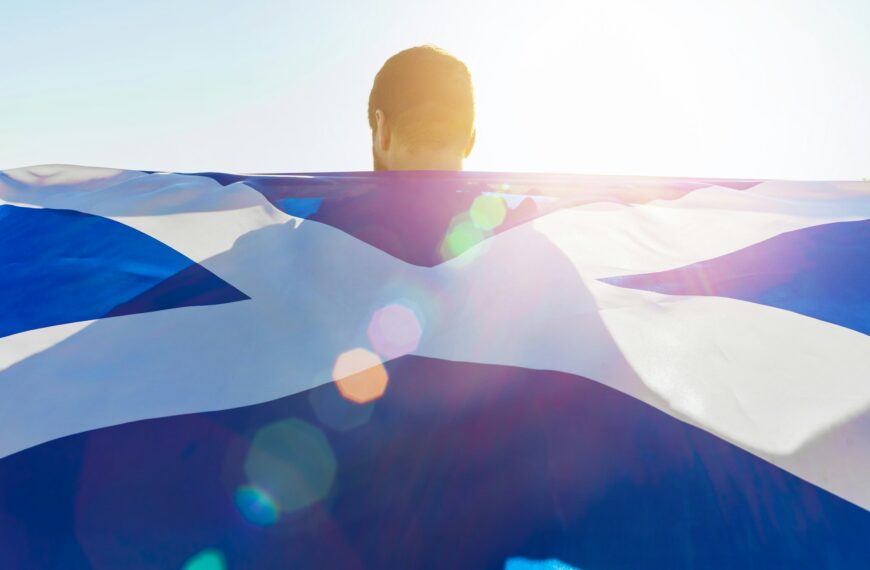 Man with a flag of Scotland standing in field