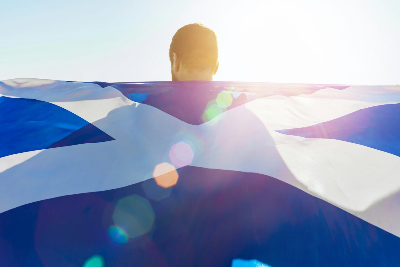Man with a flag of Scotland standing in field