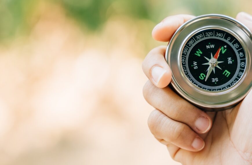 A traveler hand cradles a compass in a park symbolizing the quest for direction and guidance. Amidst