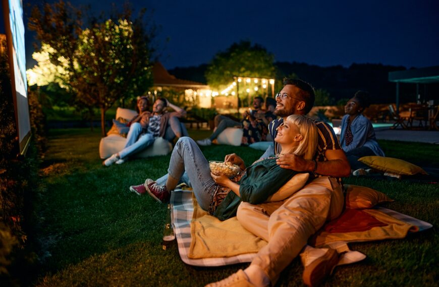 Happy couple enjoying in movie night with friends in the backyard.