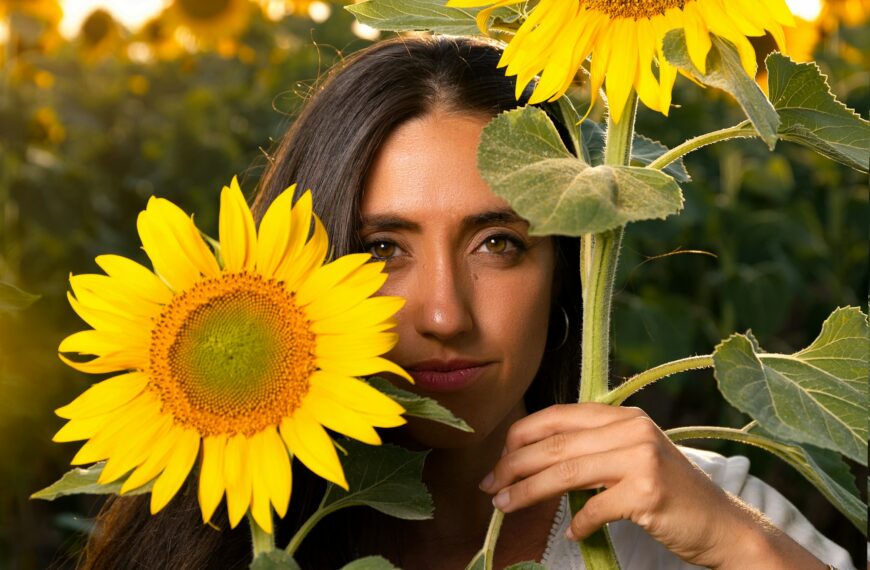 Woman among sunflowers in white dress with face behind sunflower