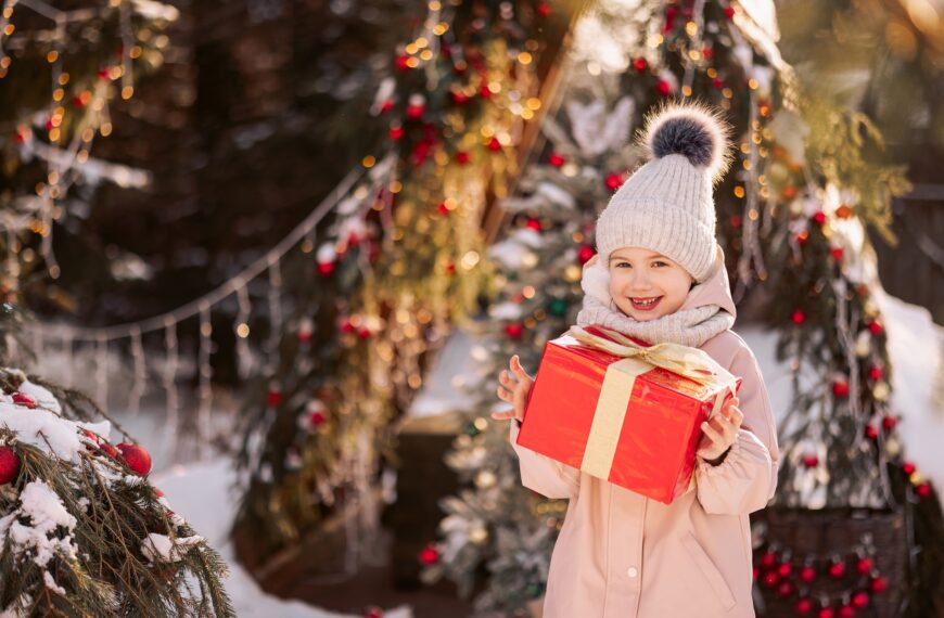 Little girl with a Christmas gift outdoors in winter on Christmas Eve.