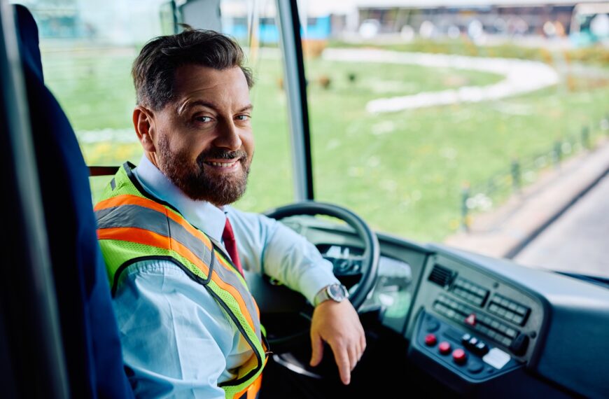 Happy bus driver inside the bus looking at camera.