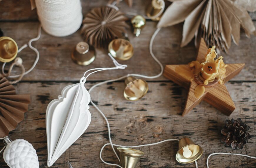 Making christmas rustic garland. Christmas bells, stars, ornaments, candle, thread. Moody image
