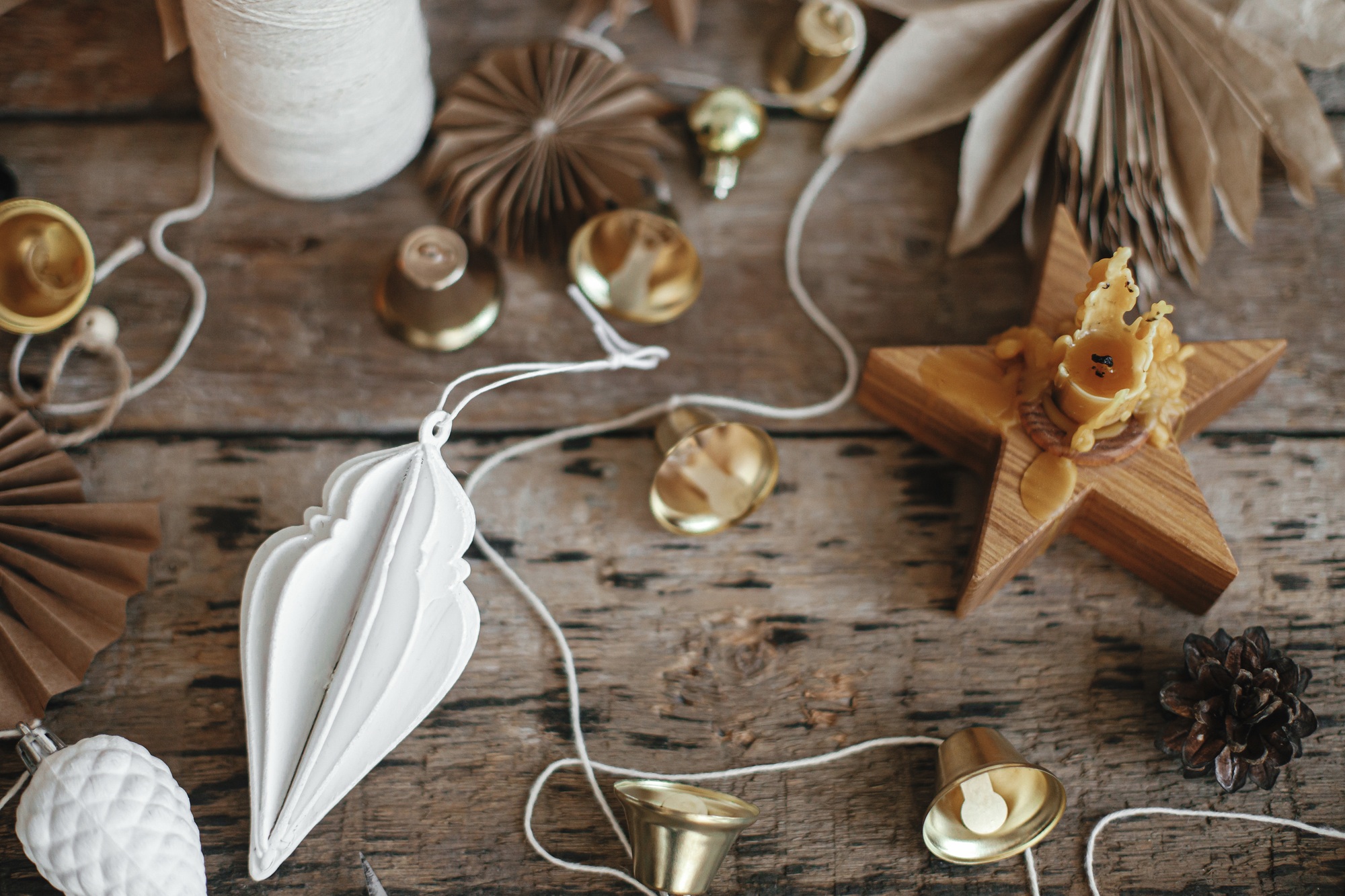 Making christmas rustic garland. Christmas bells, stars, ornaments, candle, thread. Moody image