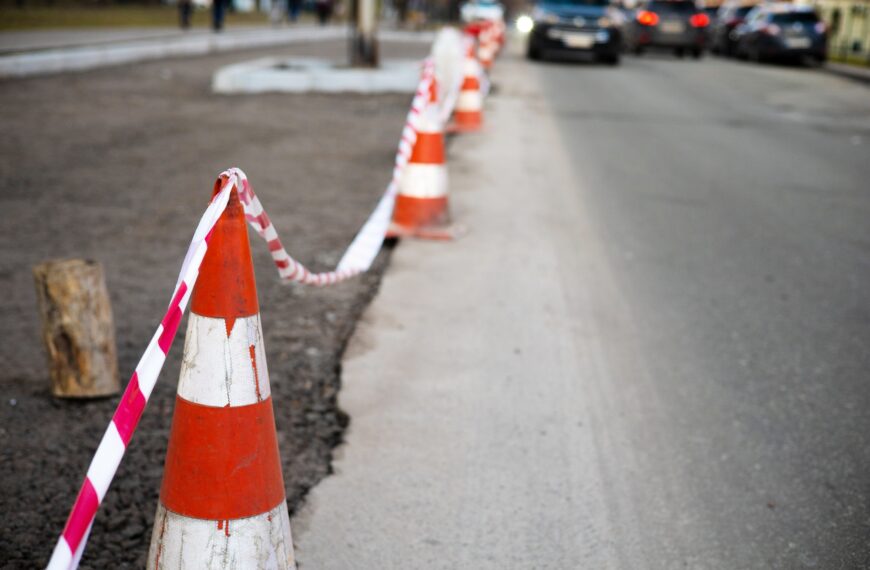 Under construction board sign on the closed road with arrow sign and traffic cone. Caution symbol un