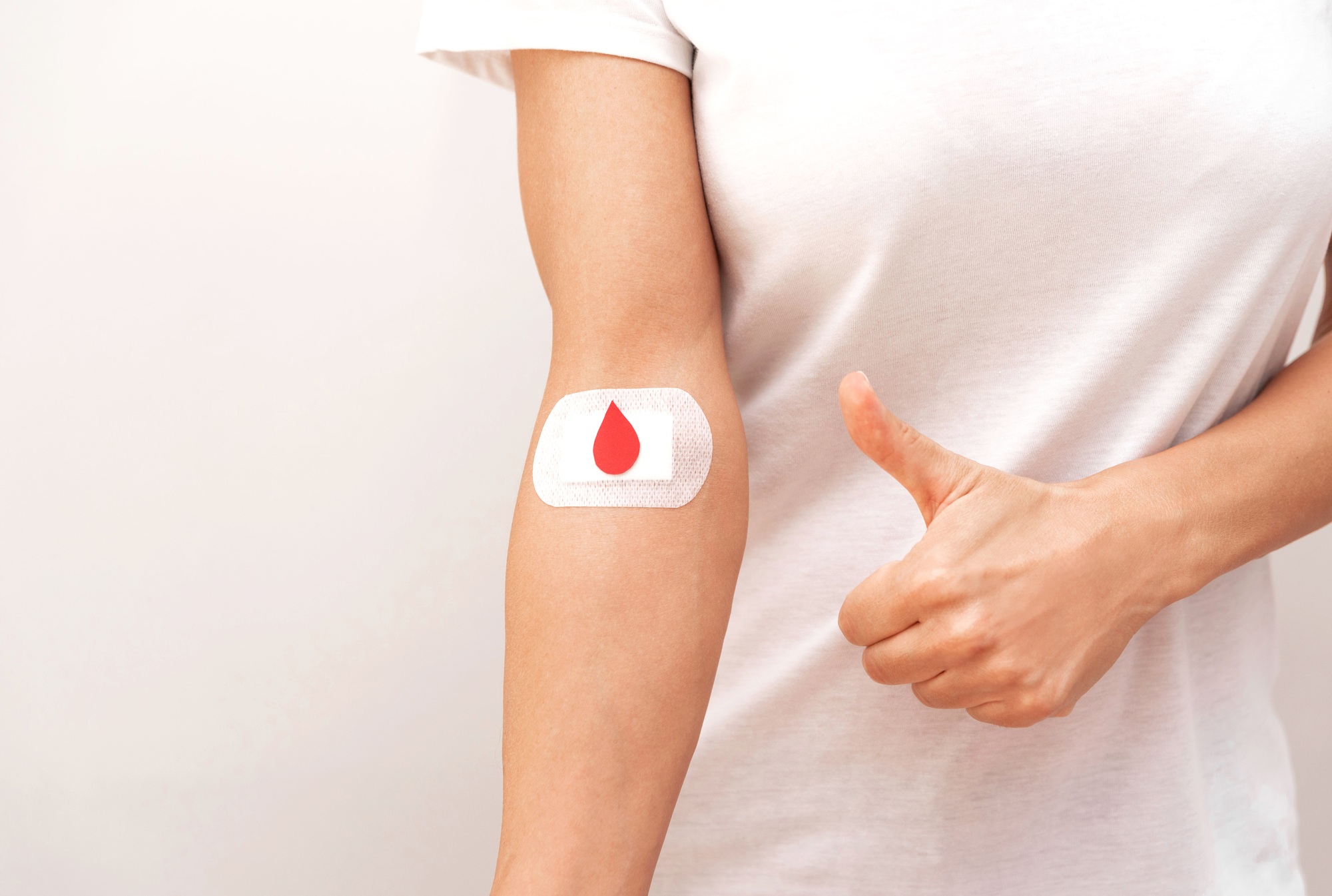 close up of Arm with a blood drop on bandage and thumbs up gesture after After Blood Donation