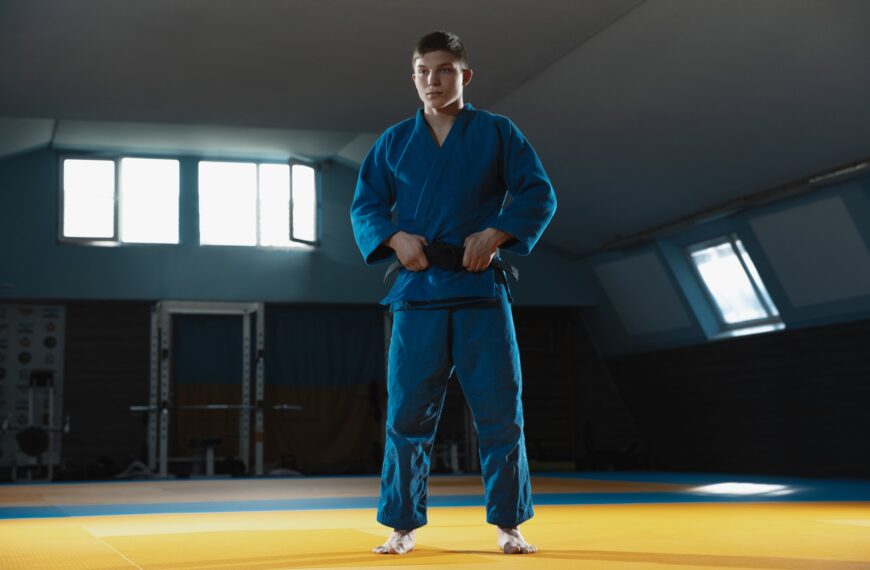 Young judo fighter in kimono posing comfident in the gym, strong and healthy