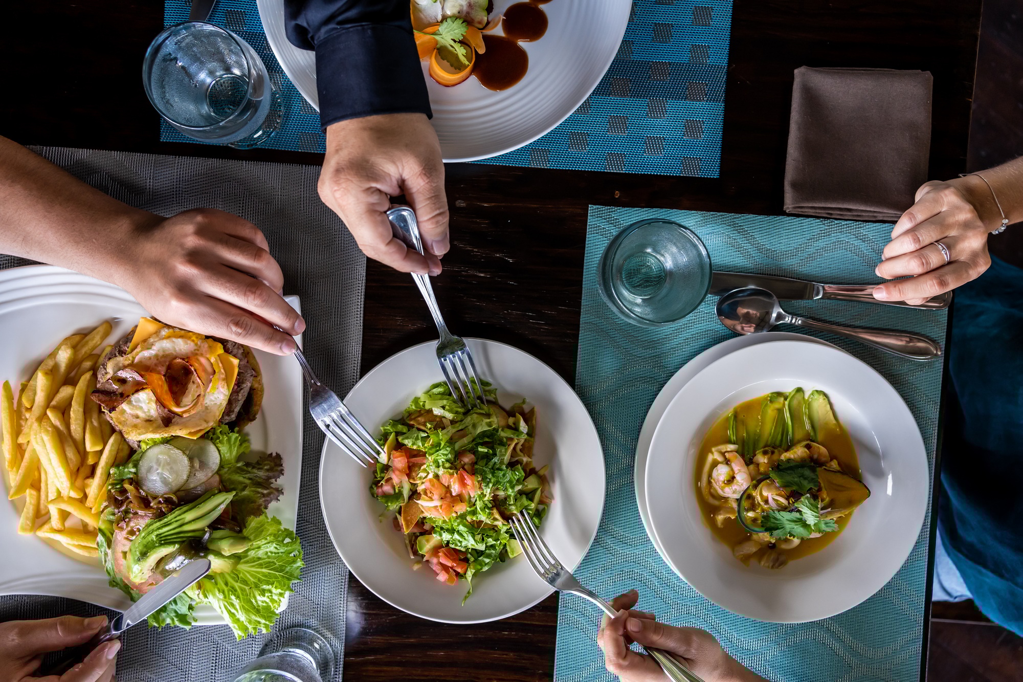 Aerial photo of people sharing the food of a raw of dishes